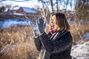 Happy young woman on a walk in winter with snow in her hands